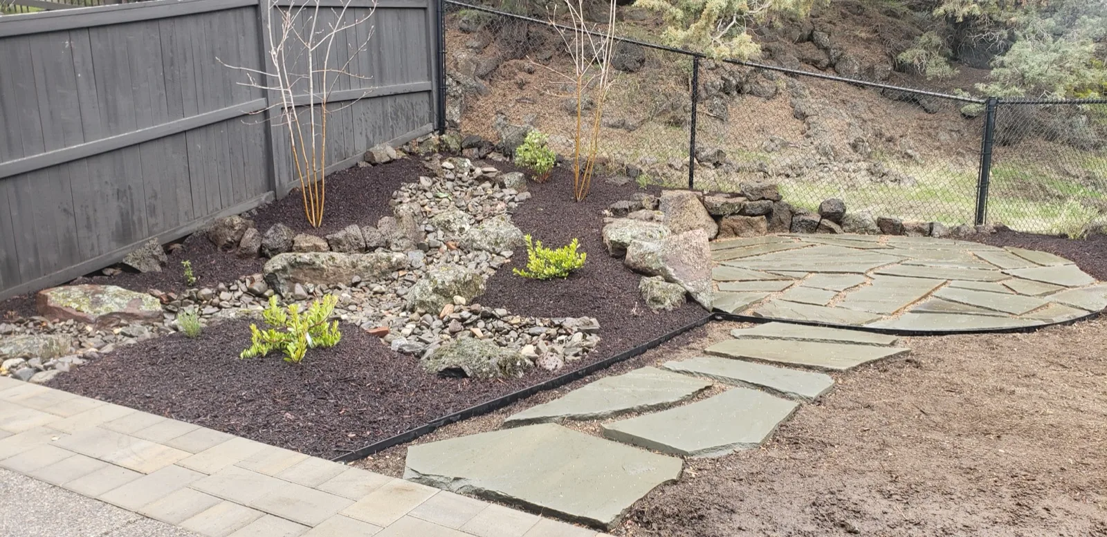 Natural dry creek bed water feature with flagstone patio and native plantings.