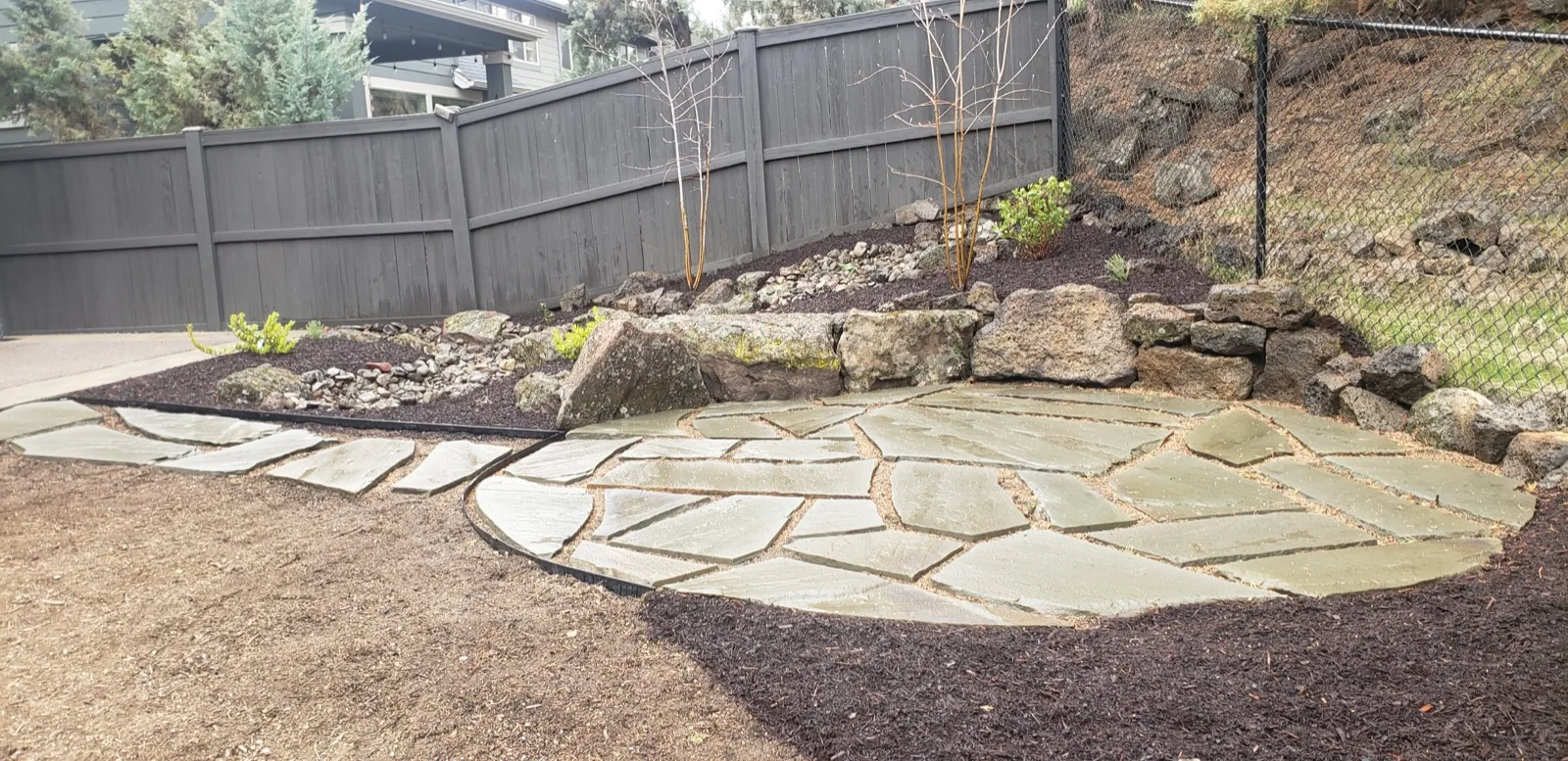 Flagstone patio surrounded by boulders and drought-tolerant plantings.